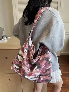 Large camouflage canvas tote bag in pink and green shown on model for daily lifestyle use