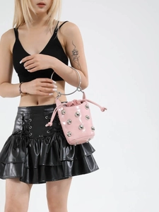 Sac seau en cuir verni rose avec rivets et poignée en métal porté par un mannequin