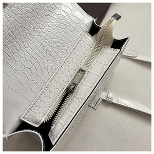 Macro detail of white crocodile embossed leather bag with silver zipper and metal lock
