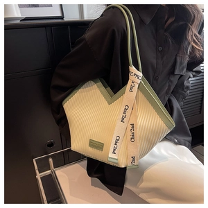 Sac cabas en toile avec garniture en cuir vert et col en V porté par un mannequin