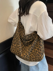 Large leopard print canvas tote bag shown worn by a model on a shoulder strap