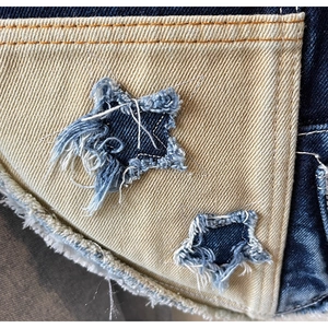 Detailansicht der Denim-Patchwork-Nähte mit Sternen-Applikation und Fransen-Effekt