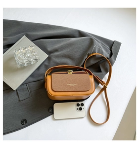 Detail showing caramel leather box bag texture with smartphone for size reference