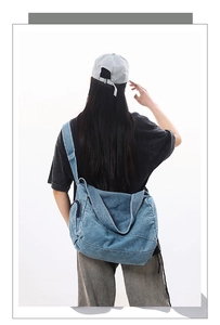 Close-up of vintage blue denim messenger bag on model showing large capacity and texture