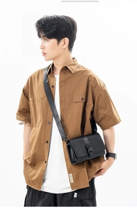 Close-up of minimalist black messenger bag with flap cover and buckle on a male model