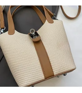 Detail of the bucket bag showing beige canvas, brown leather straps, and silver ring lock