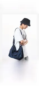 Deep blue washed denim messenger bag shown on model for visual scale and drape