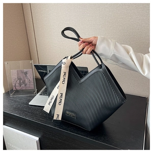 Détail du sac fourre-tout plissé noir avec ouverture en V et ruban décoratif lettré blanc