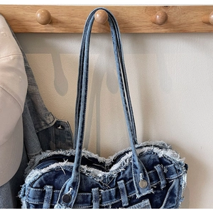Detailansicht der ausgefransten Kanten und des Metallknopfs dieser Denim-Tasche