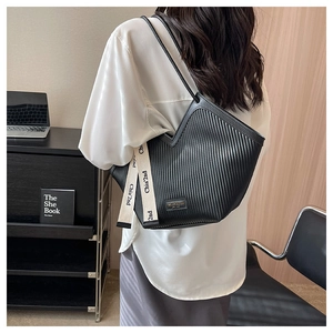 Détail du sac cabas plissé noir montrant des plis verticaux et un ruban lettré chic