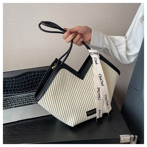 Détail d'un sac cabas plissé beige avec bordure noire et foulard décoratif en soie
