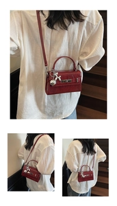 Detail of dark red patent leather handbag with silver balloon dog charm and top handle