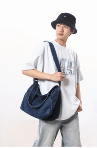 Detail of deep blue washed denim travel bag with wide shoulder strap and clean stitching