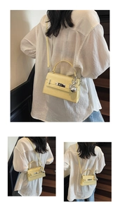 Detail of light yellow lychee grain leather bag with silver buckle and bear charm