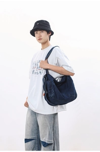 Street style shot of a large washed denim crossbody bag worn with casual white t-shirt