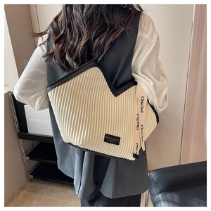 Détail du cabas plissé crème avec bordure noire et bandoulière tissée logotypée