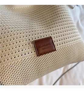 Close-up of knit tote bag featuring a hollow mesh weave and brown leather brand label