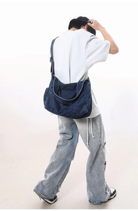 Close-up of oversized dark blue washed denim crossbody bag with contrast white stitching