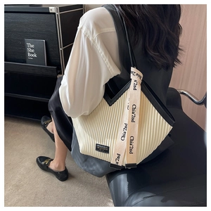 Vue détaillée du sac cabas beige plissé avec sangle graphique noire et écusson logo