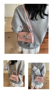 Macro detail of pink textured leather bag with silver buckle and metallic bear charm