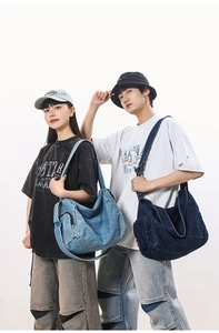 Detail of washed denim travel bags in light and dark blue showing spacious multi-pocket design