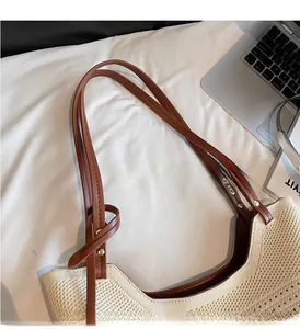 Detail of sturdy brown leather handles and weave texture on the beige tote bag