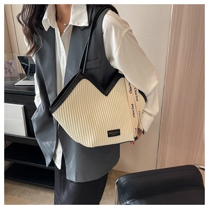 Détail du sac fourre-tout plissé beige avec écusson logo noir et bandoulière tissée