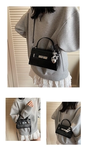 Detail of black crocodile texture handbag with silver twist lock and bunny charm
