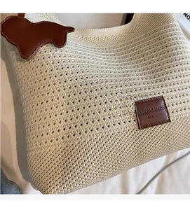 Detailed macro view of the cream knit mesh texture with a brown leather puppy charm
