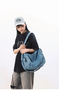 Detailed view of large washed denim shoulder bag featuring functional side zipper pocket