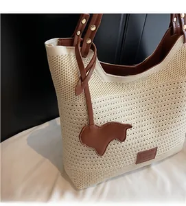 Detail of hollow knit texture and brown leather strap with metal rivets on tote bag