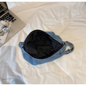Internal view of blue denim hobo bag featuring black lining and functional inner pocket
