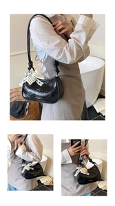 Detail of black patent leather crescent bag with pearl heart and lace bow accent