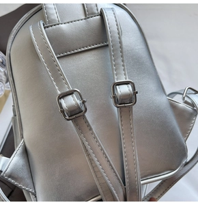 Detail of silver metallic quilted backpack featuring adjustable straps and top handle
