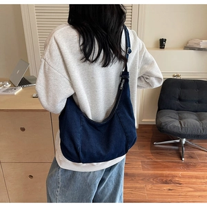 Deep blue denim hobo bag with adjustable wide shoulder strap shown on a female model
