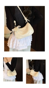 Close-up of cream half-moon cloud bag with pearl bow charm and glossy leather texture