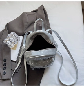 Detail of silver metallic mini backpack with quilted pattern and rivet pocket on a suit