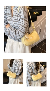Detail of yellow pleated cloud bag with pearl chain and lace bow in lifestyle setting