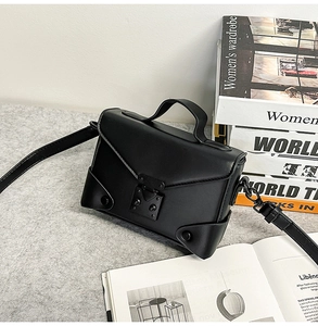 Detail view of structured black PU leather crossbody bag with metallic buckle and rivets