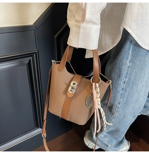 Close-up of woven bucket bag with leather trim and silver metal twist-lock buckle