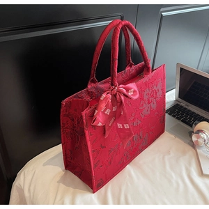 Close-up of red wedding tote bag featuring intricate floral embroidery and silk ribbons