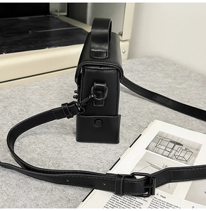 Detail view of the matte black faux leather small square bag with metal D-ring attachment