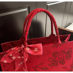 Close-up of red wedding tote bag featuring floral jacquard and silk bow with double joy symbol