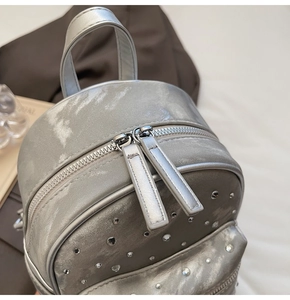 Detailed close-up of metallic silver quilted backpack featuring sparkling rhinestone accents