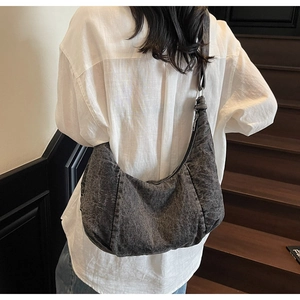 Back view of a large washed black denim hobo bag worn as a comfortable shoulder bag