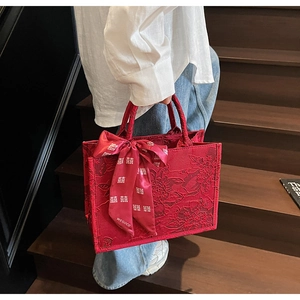 Detail of red floral lace wedding tote bag with decorative silk ribbon on the handle