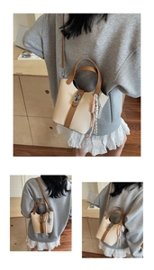 Detail of woven straw bucket bag featuring brown leather trim and silver metal buckle