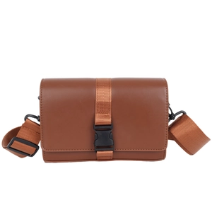 Close-up of brown faux leather box bag showing black plastic buckle and nylon strap