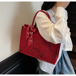 Detail of red jacquard tote bag with traditional floral pattern and silk bow decoration