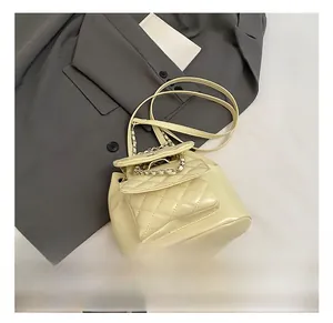 Detail view of cream quilted mini backpack with chain handle on a grey blazer